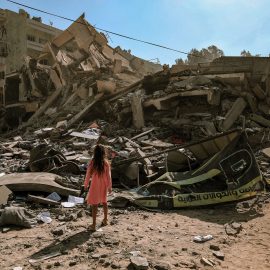 Ein Mädchen steht hilflos vor dem Trümmerhaufen eines Wohnhauses