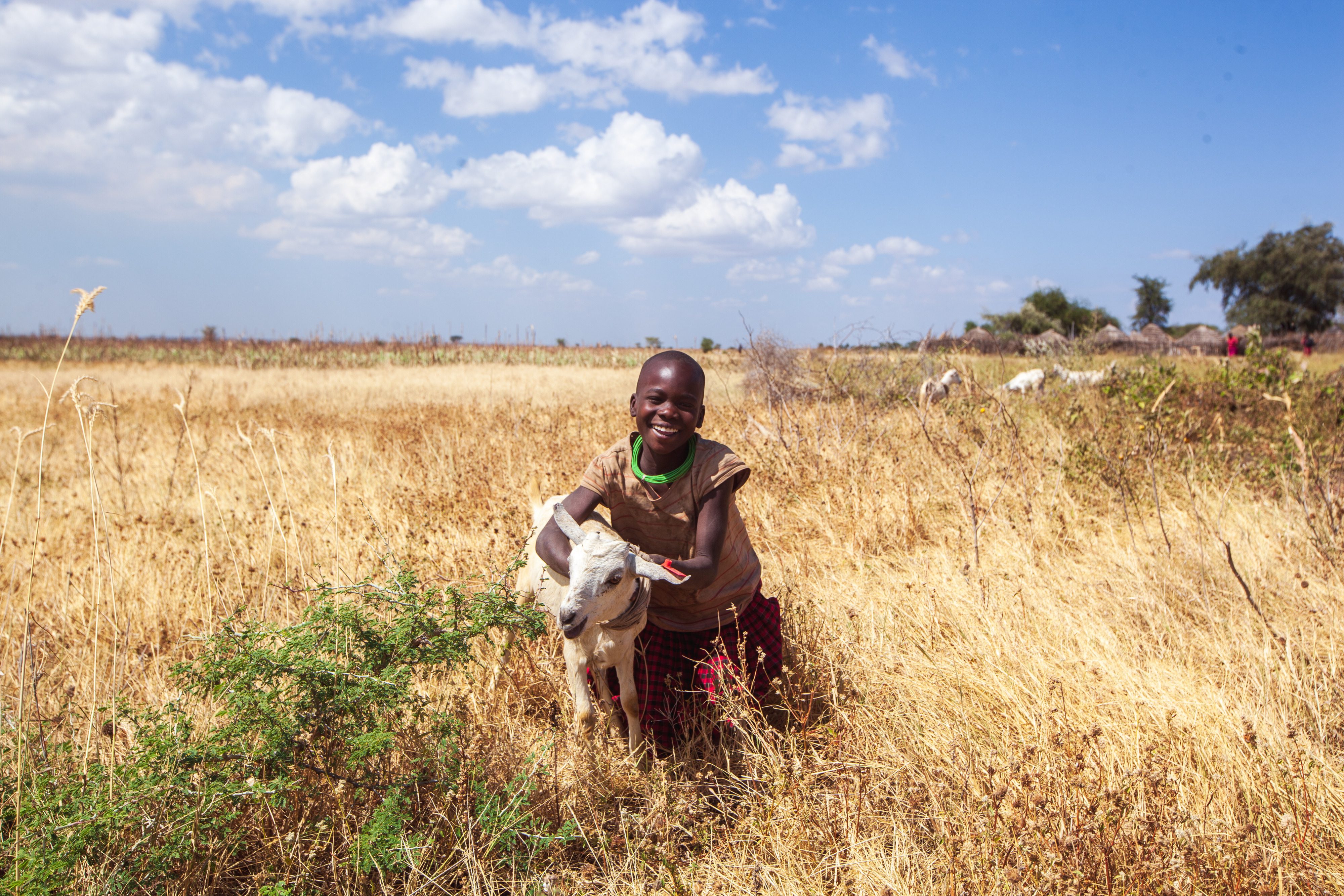 Sarah (8) posiert auf den Feldern mit einer Ziege ihrer Mutter.