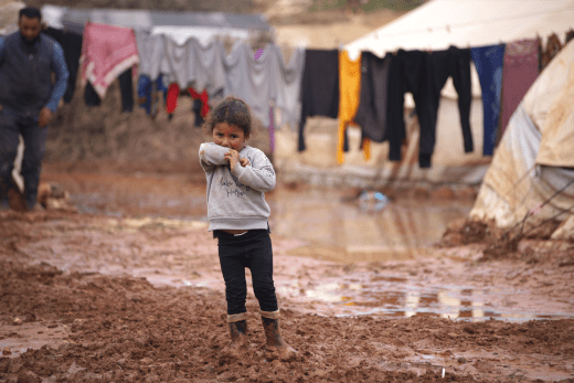 Ein Mädchen steht vor dem Zelt ihrer Familie in einem Flüchtlingslager in Syrien.